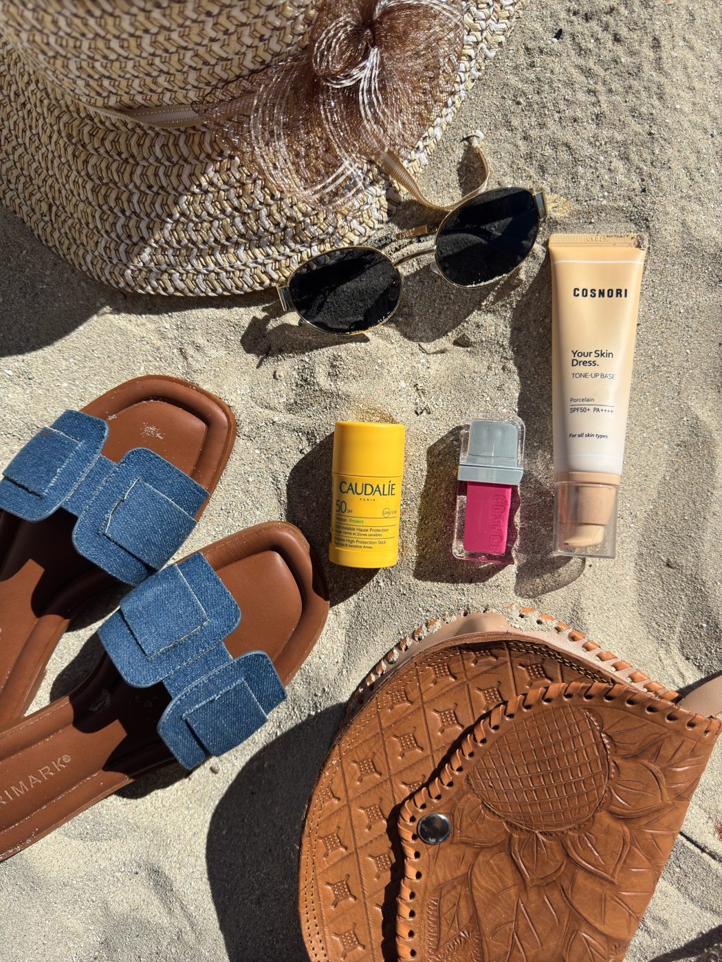 Sunscreen, lip tint and beach accessories flat lay
